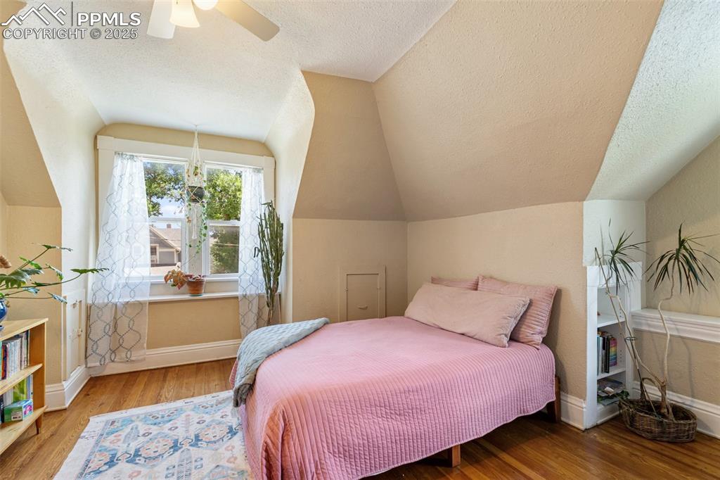 Bedroom featuring a textured ceiling, wood finished floors, lofted ceiling, and a ceiling fan