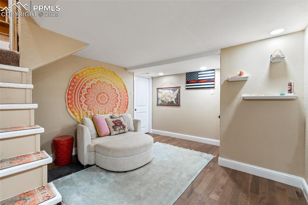 Sitting room with wood finished floors, a textured wall, and recessed lighting