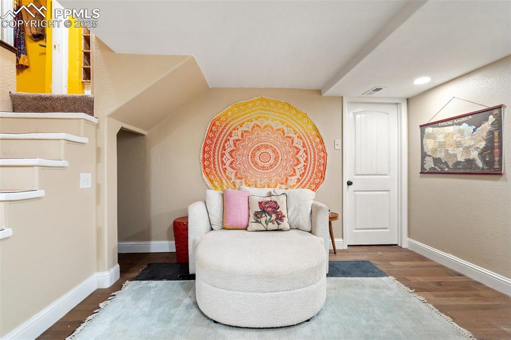 Sitting room with wood finished floors and stairway