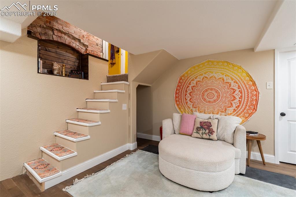 Living area featuring wood finished floors, stairs, and a textured wall