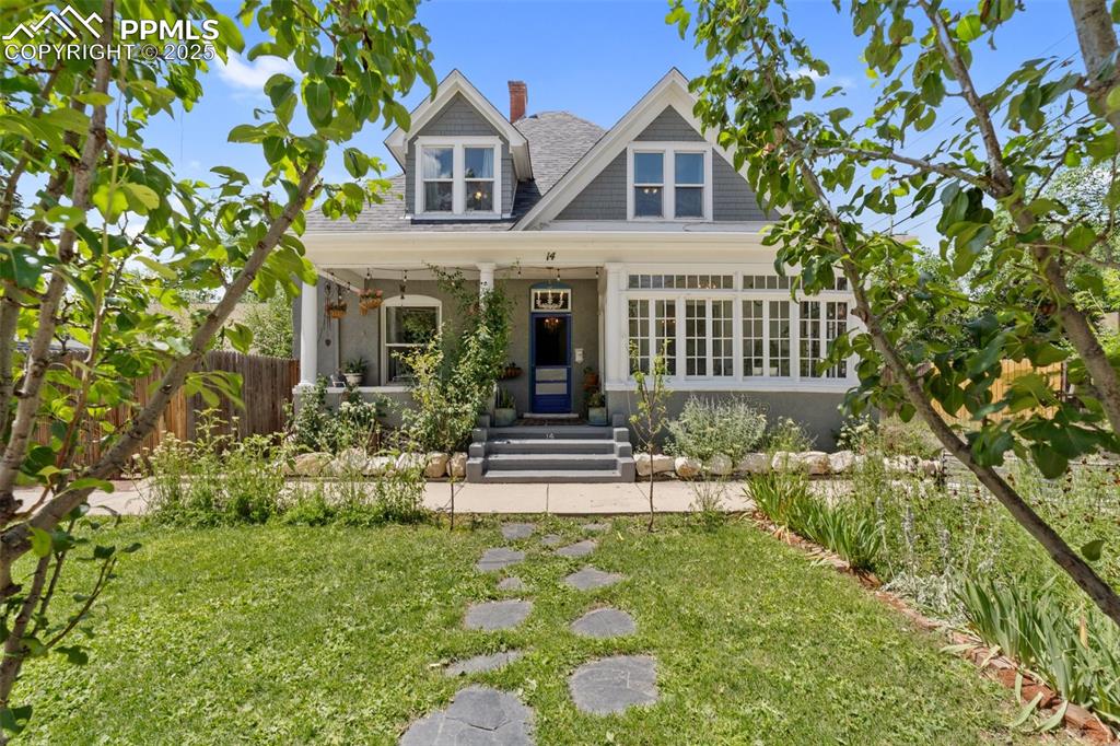 View of front facade with a porch, a chimney, and roof with shingles