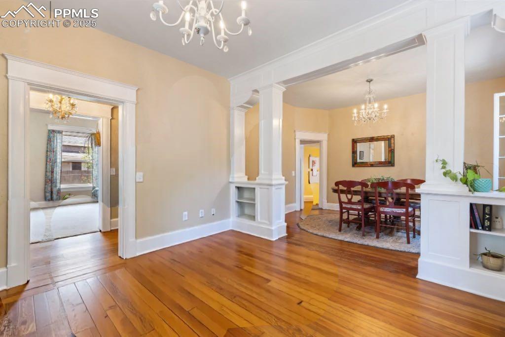 Dining space with a chandelier, decorative columns, and hardwood / wood-style floors