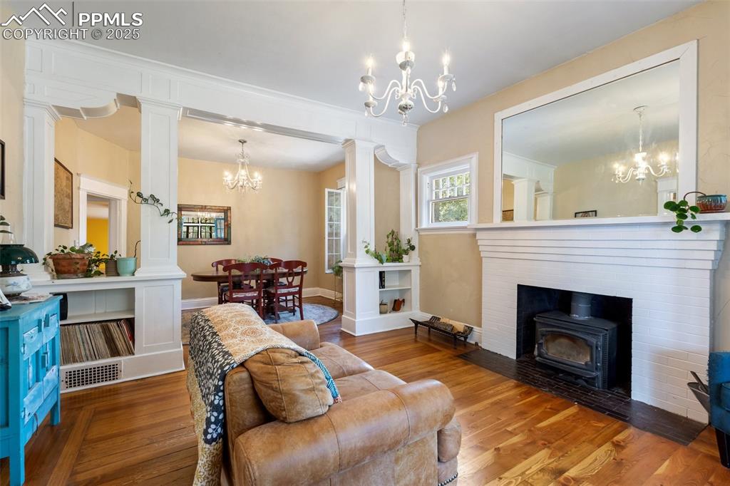 Living area featuring a chandelier, wood finished floors, and decorative columns