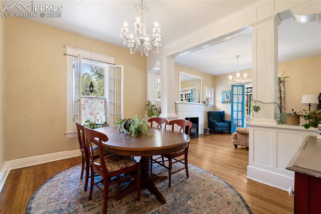 Dining room with decorative columns, light wood-style flooring, a fireplace with flush hearth, and plenty of natural light