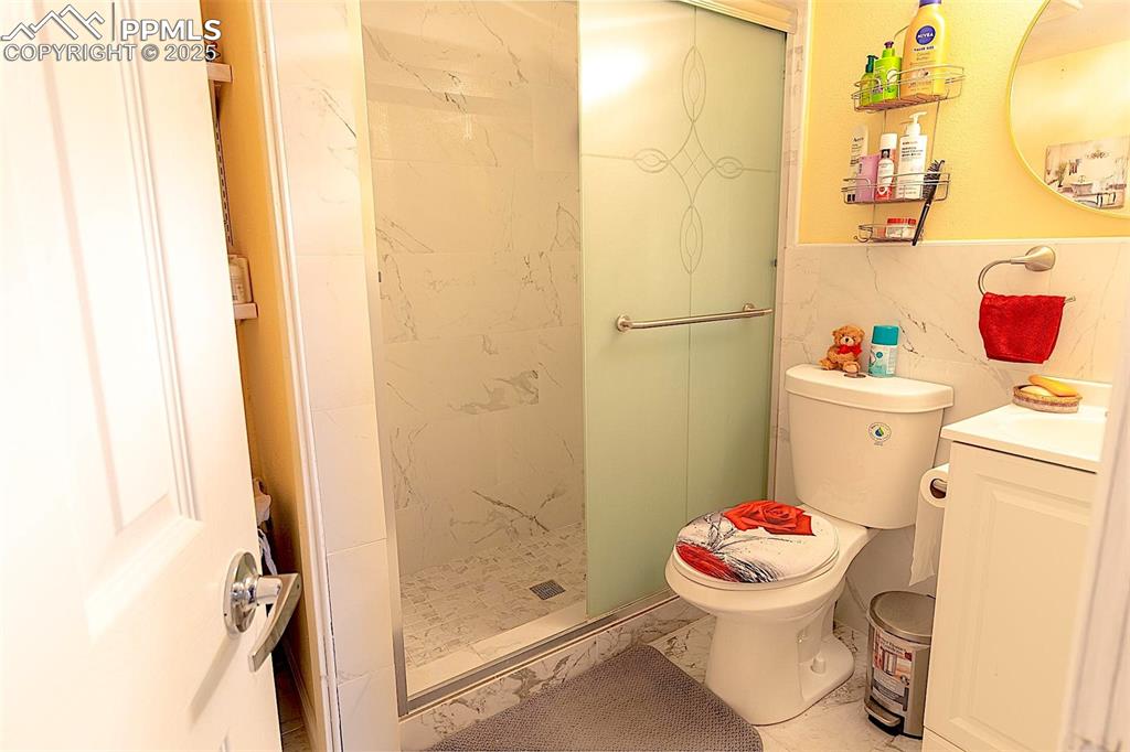 Full bathroom featuring marble finish floors, vanity, toilet, and a shower stall
