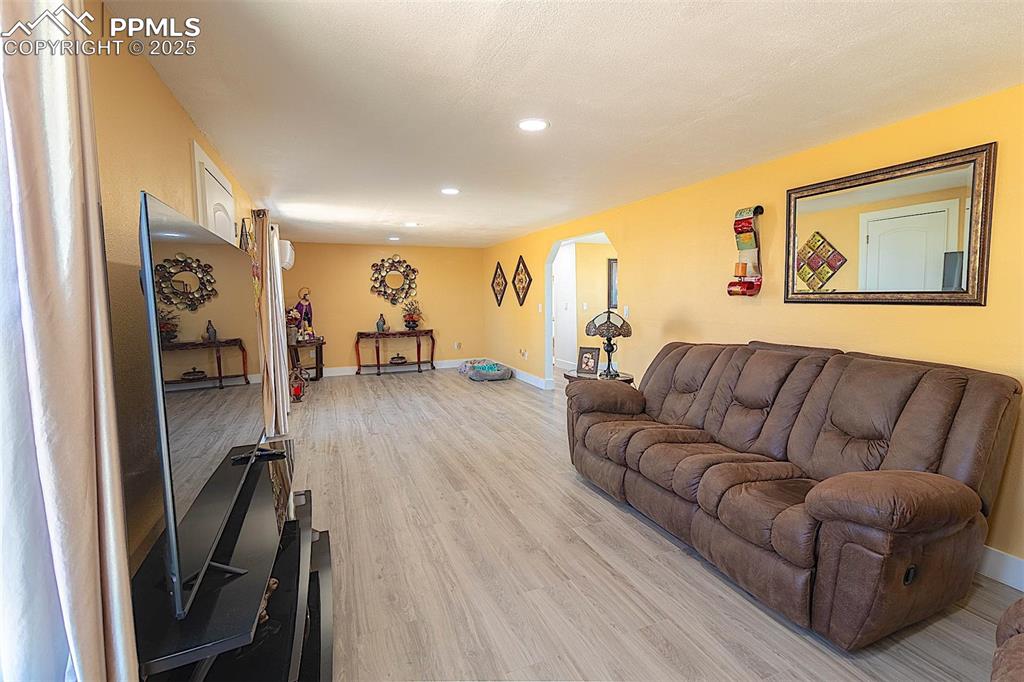 Living room featuring recessed lighting, light wood-style floors, arched walkways, and baseboards