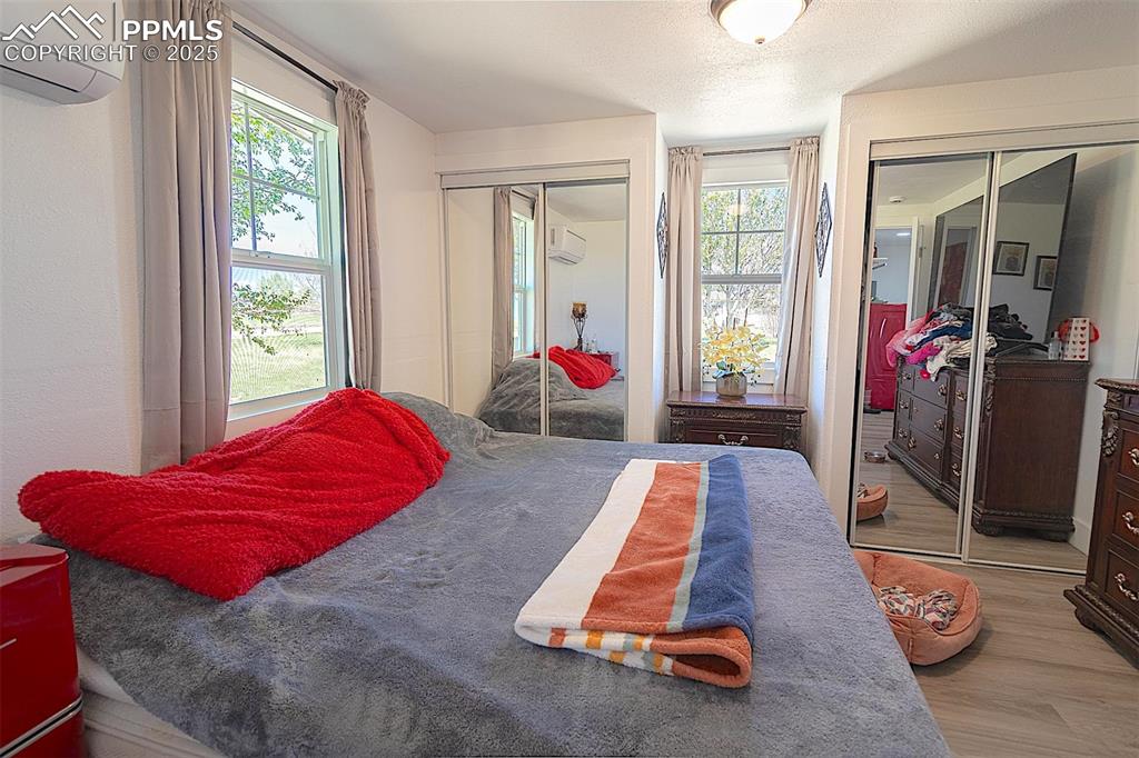 Bedroom with an AC wall unit, two closets, and wood finished floors