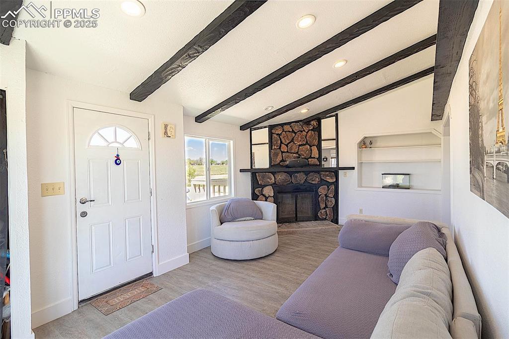 Living area with recessed lighting, a stone fireplace, wood finished floors, and baseboards