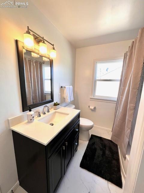 Full bathroom featuring vanity, plenty of natural light, and light marble finish flooring