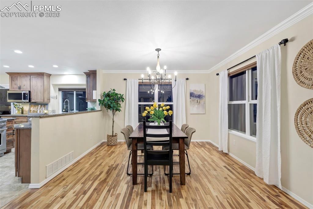 Dining space with light wood-style floors, a chandelier, and crown molding