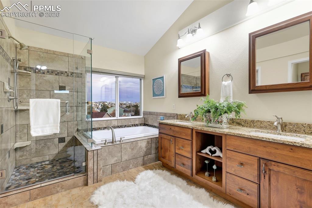 Full bathroom with a bath, double vanity, a stall shower, and vaulted ceiling