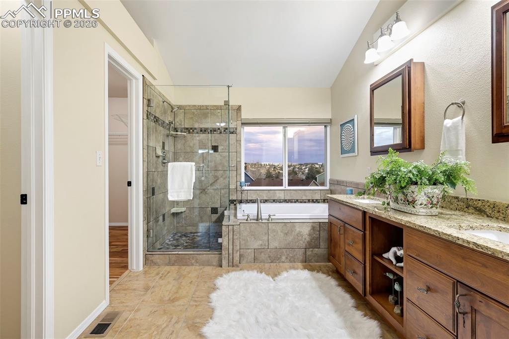 Bathroom with a garden tub, a shower stall, double vanity, a spacious closet, and light tile patterned flooring