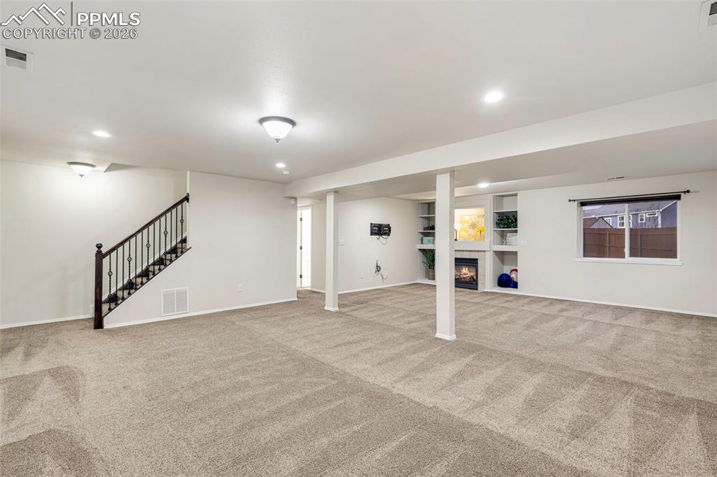 Basement featuring a tile fireplace, light carpet, and recessed lighting