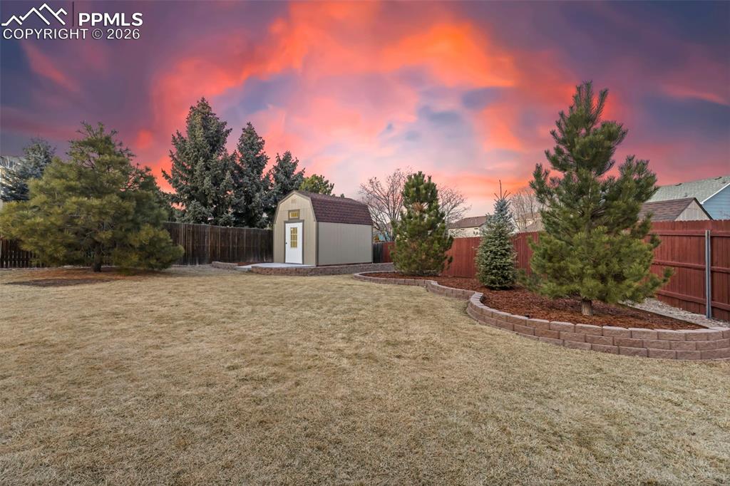 Yard at dusk featuring a fenced backyard and a storage shed
