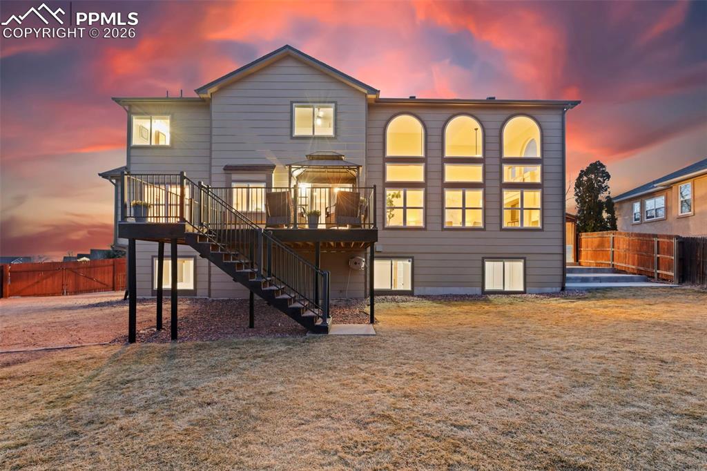 Back of house at dusk featuring a fenced backyard, a patio, and a deck
