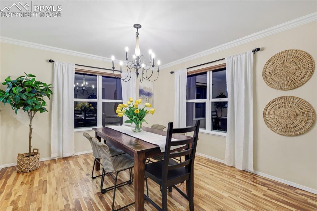 Dining area featuring ornamental molding, light wood-style flooring, and hanging lights