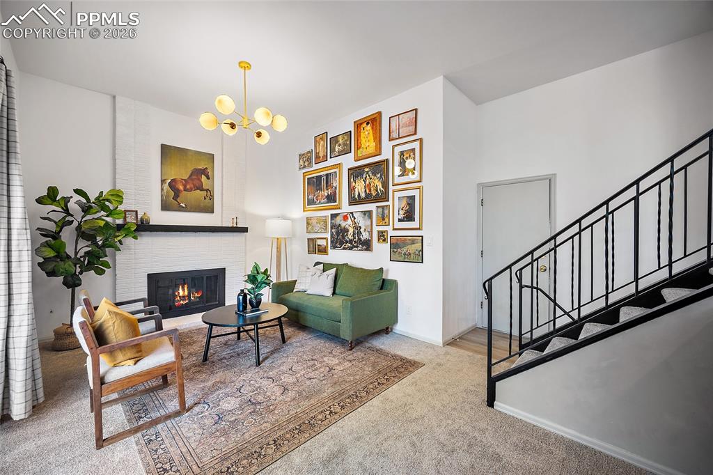 Carpeted living room with a chandelier and a brick fireplace, door to the garage
