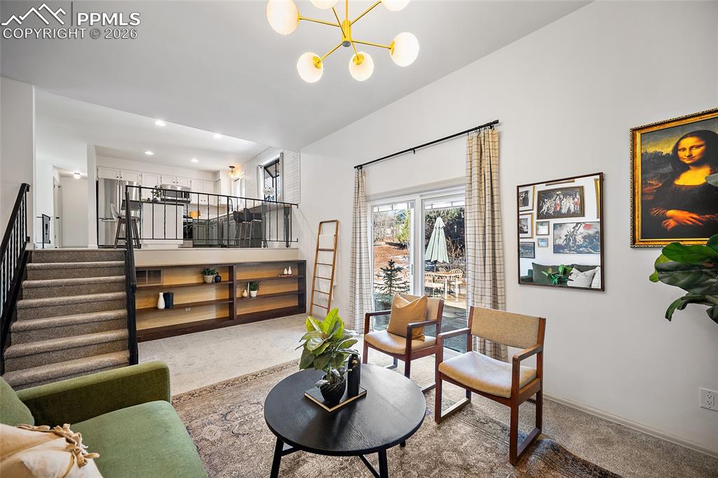 Carpeted living area with stairs and suspended lighting