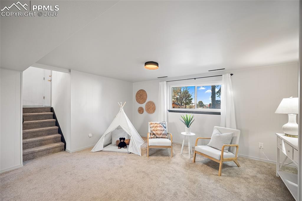 Sitting room featuring stairs and light carpet, tons of natural light, basement living room