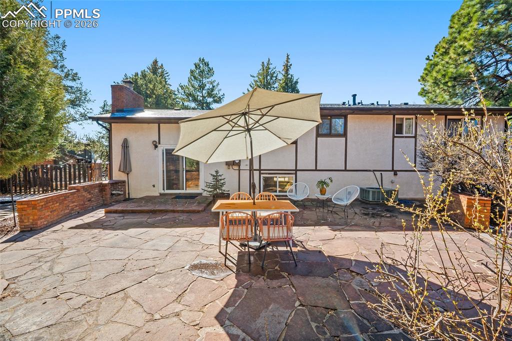 Rear view of house featuring a chimney, a patio area, outdoor dining area, and stucco siding