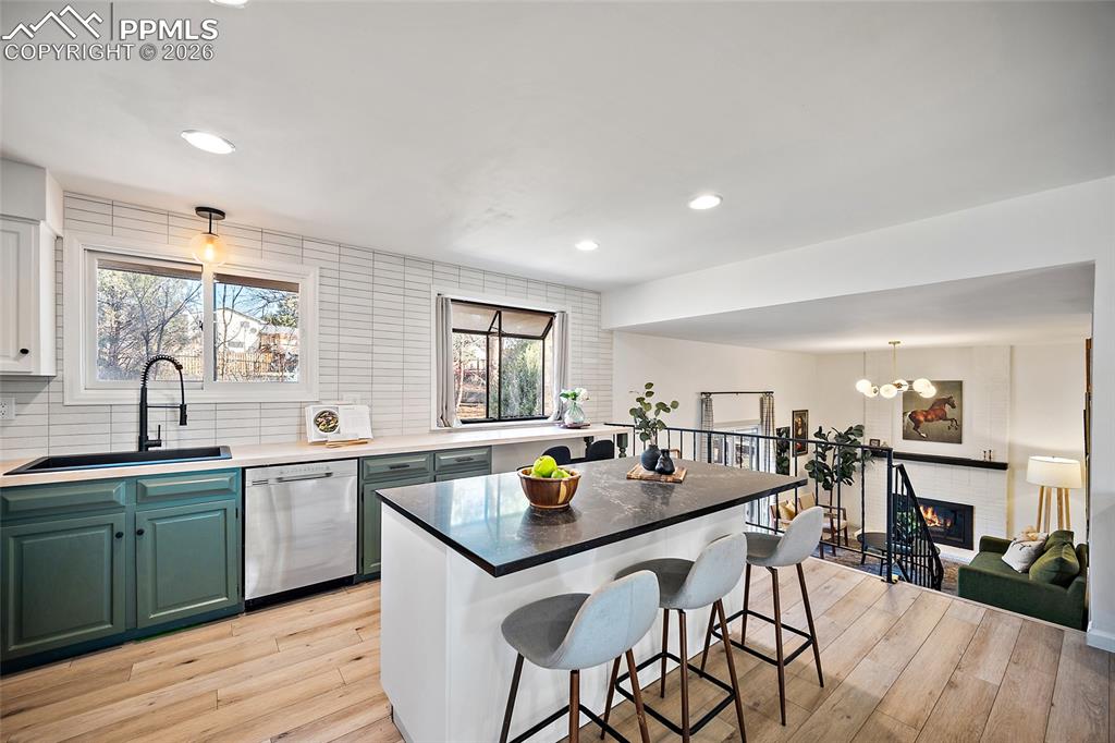 Kitchen featuring pendant lighting, a breakfast bar area, custom backsplash, and dishwasher
