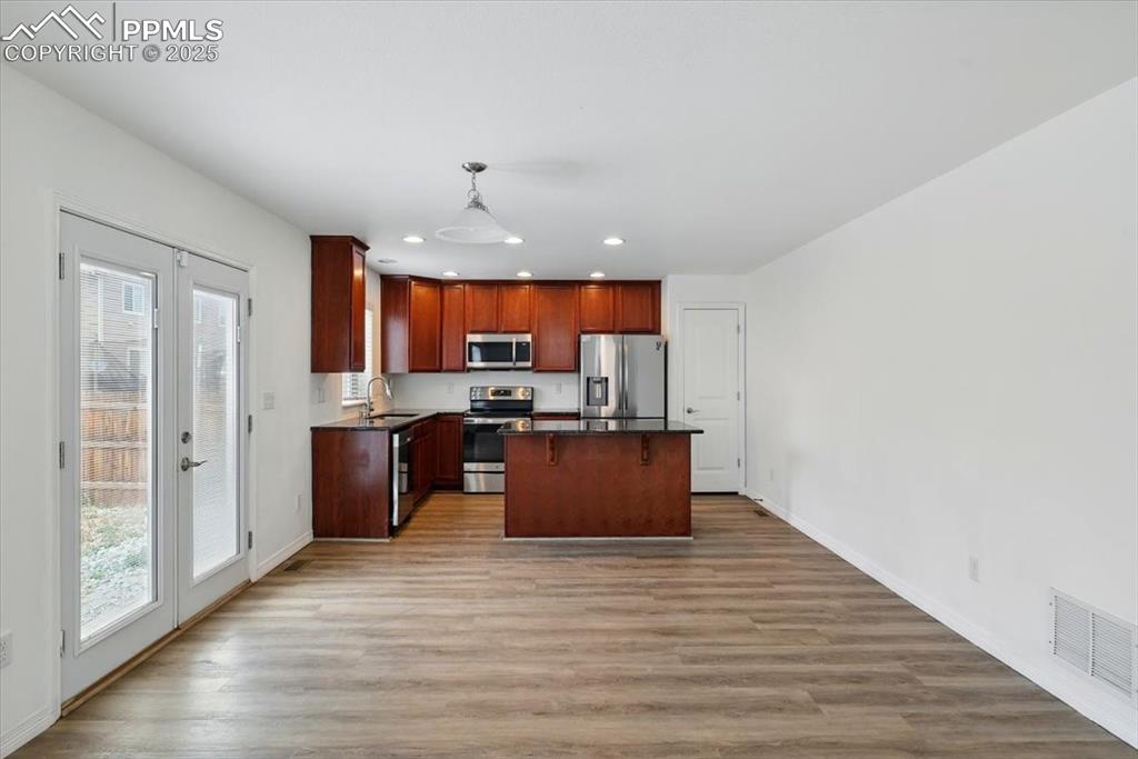 Kitchen featuring appliances with stainless steel finishes, dark countertops, recessed lighting, plenty of natural light, and a kitchen island