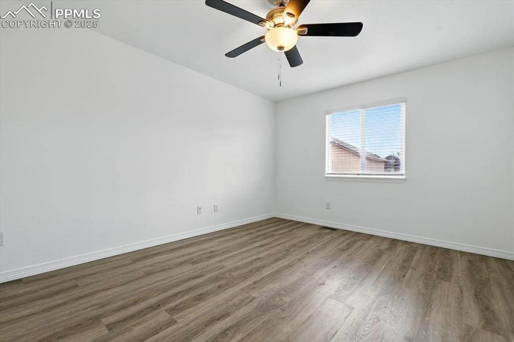 Empty room featuring wood finished floors, baseboards, and a ceiling fan