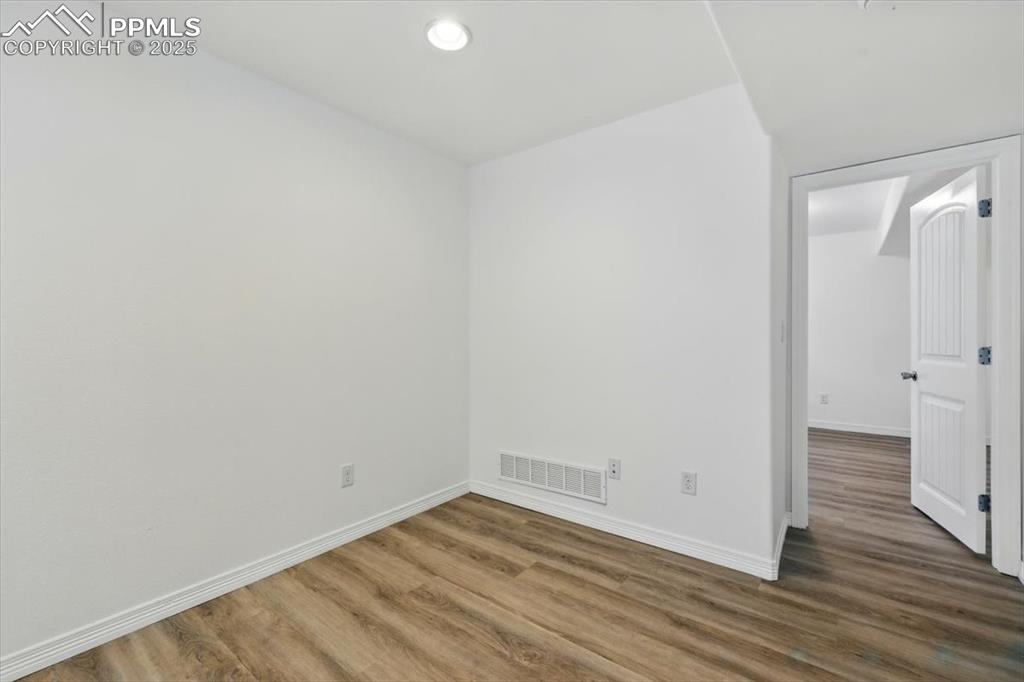 Empty room featuring wood finished floors, baseboards, and recessed lighting