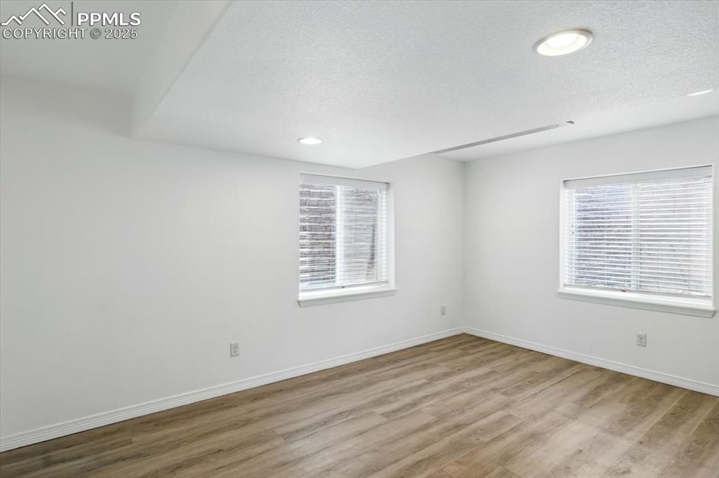 Spare room with wood finished floors, a textured ceiling, baseboards, and recessed lighting