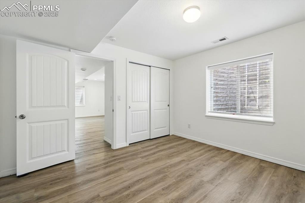 Unfurnished bedroom featuring wood finished floors, baseboards, and a closet
