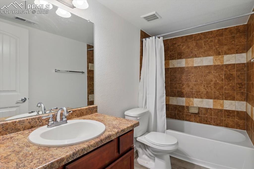 Full bath with vanity, toilet, and shower / bath combination with curtain