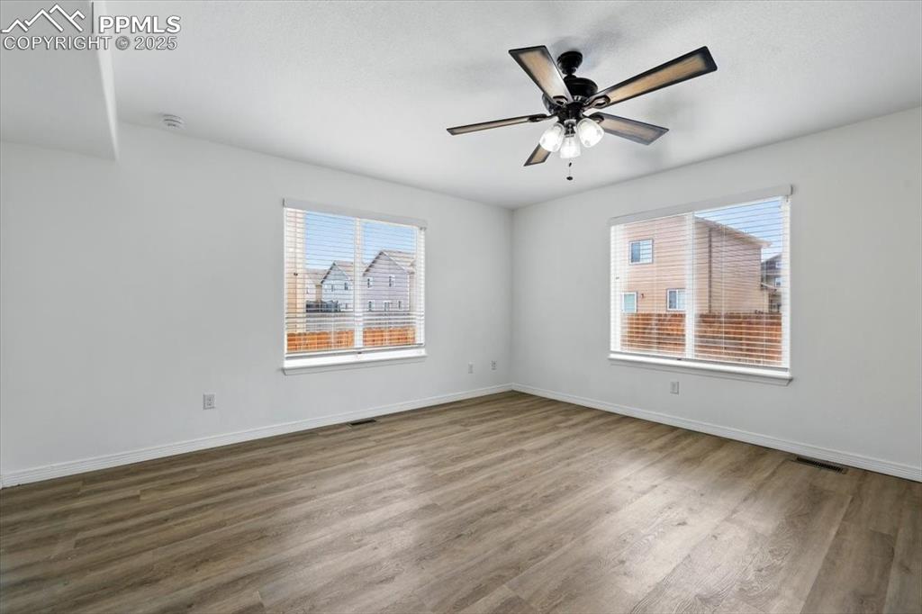 Spare room featuring wood finished floors, baseboards, a ceiling fan, and a smoke detector