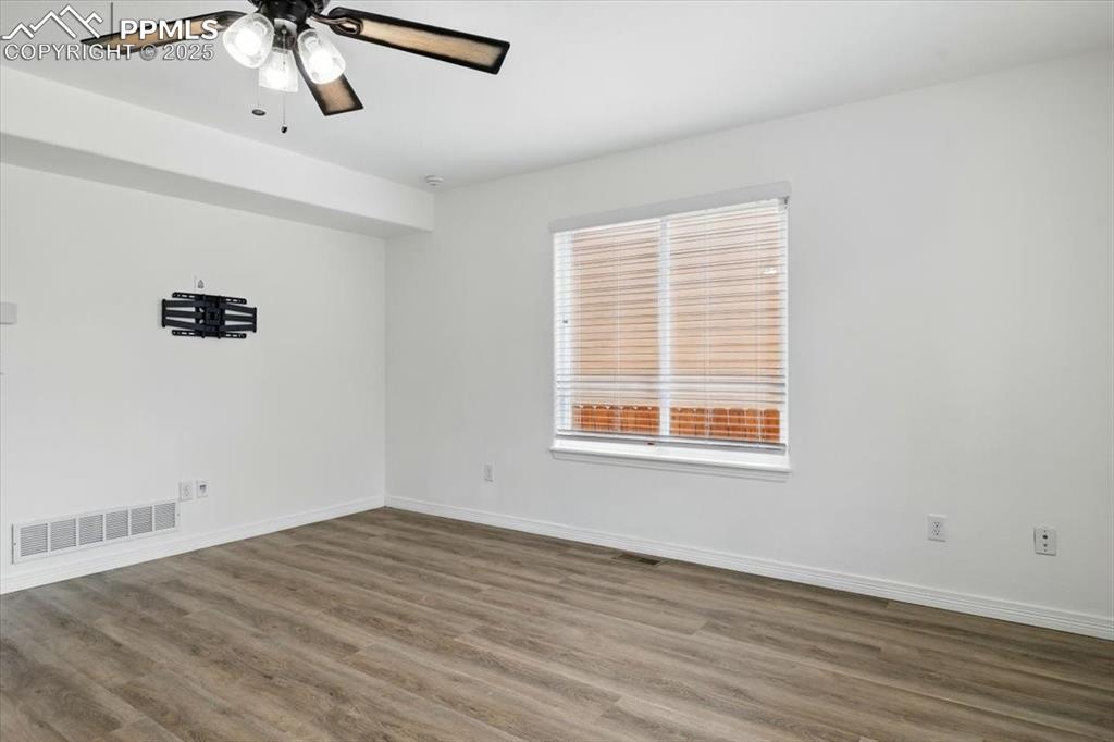 Unfurnished room featuring wood finished floors, baseboards, and ceiling fan