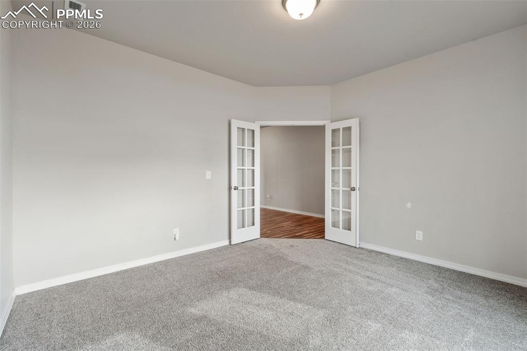 Unfurnished room featuring french doors and carpet flooring