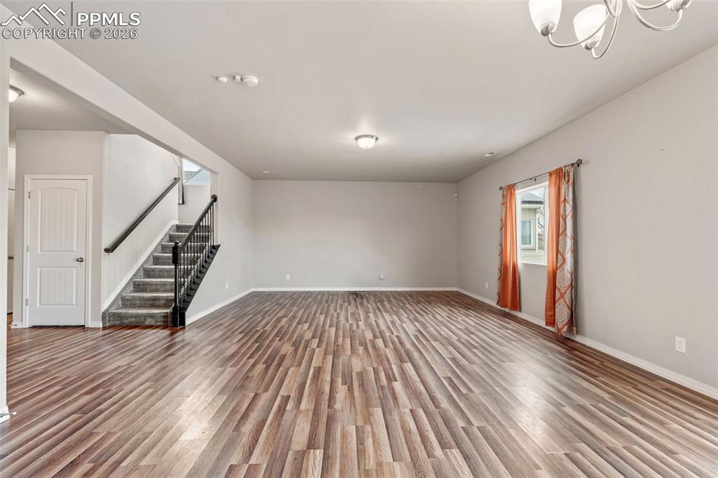 Empty room featuring wood finished floors and suspended lighting