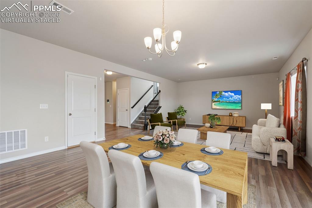 Virtually staged. Dining room with a chandelier and dark wood finished floors