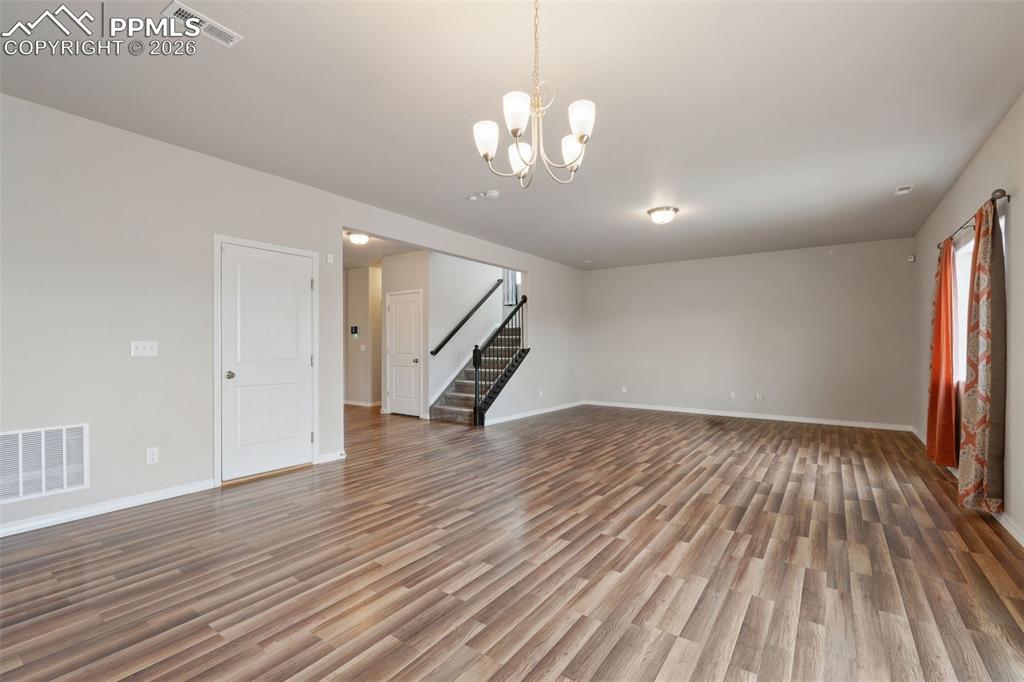 Unfurnished living room with light wood-style floors and suspended lighting