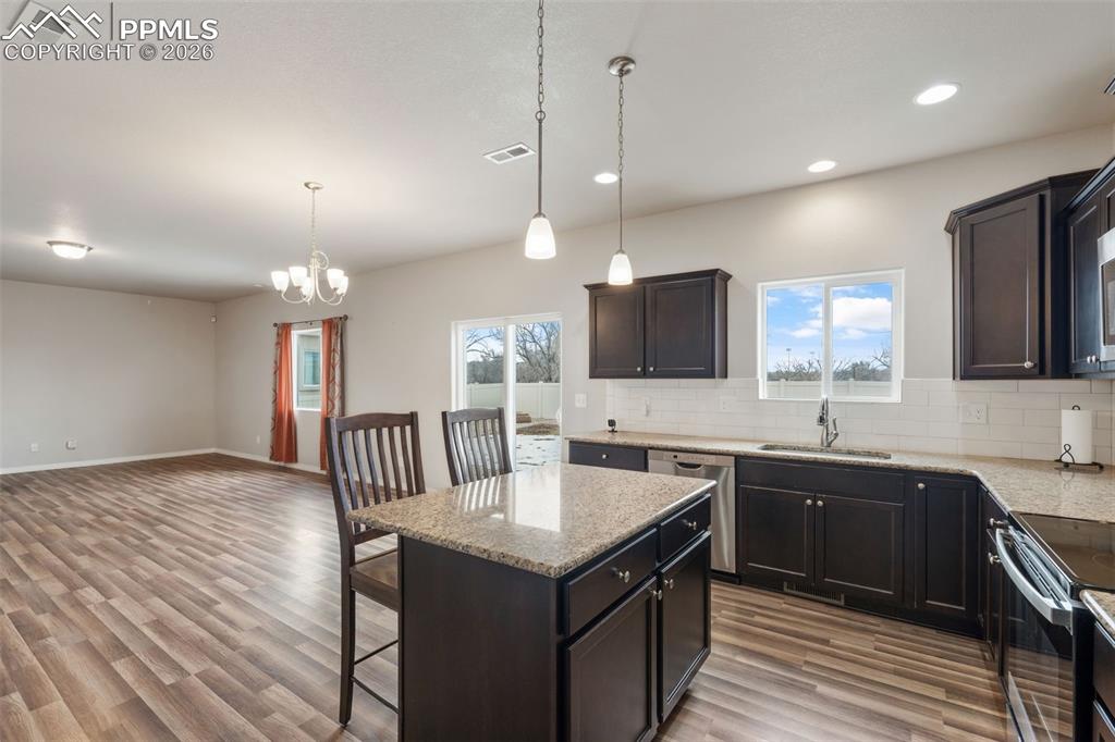 Kitchen featuring a breakfast bar area, light stone counters, a kitchen island, and tasteful backsplash