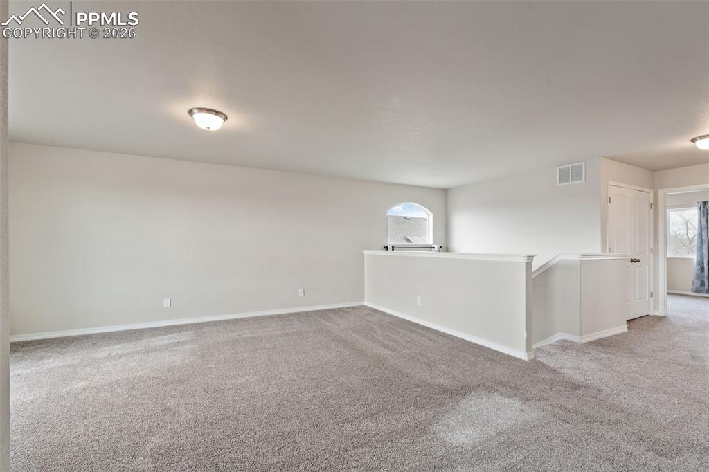 Unfurnished room featuring light carpet and plenty of natural light