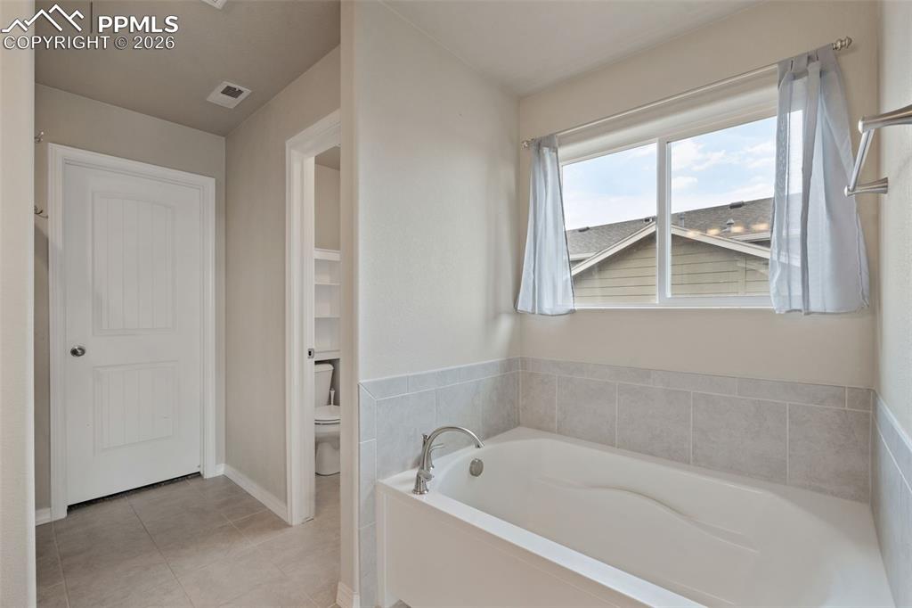 Full bath featuring a garden tub and light tile patterned floors