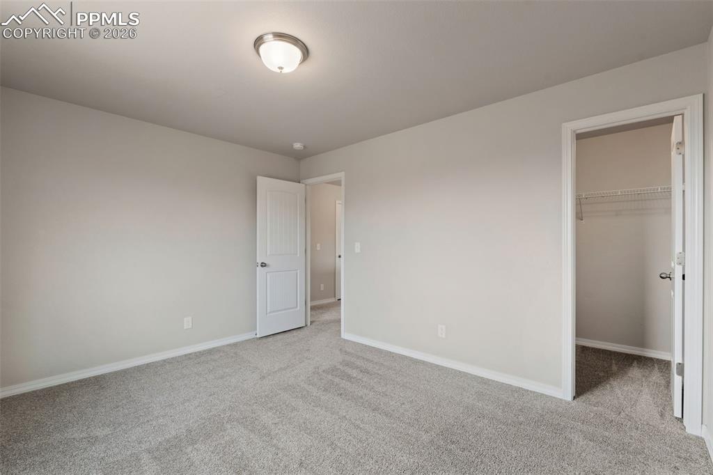 Unfurnished bedroom featuring a spacious closet and light carpet