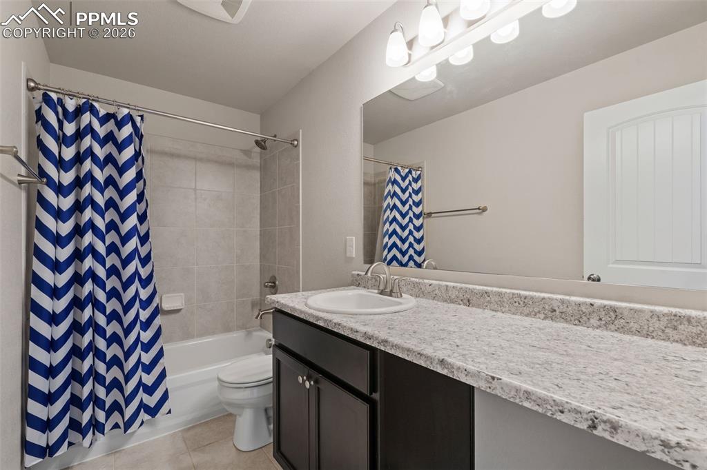 Bathroom featuring vanity, shower / bath combo with shower curtain, and light tile patterned flooring