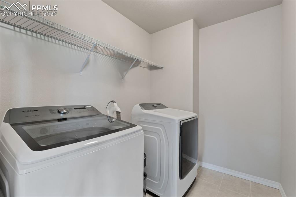 Laundry area with washer and clothes dryer and light tile patterned flooring