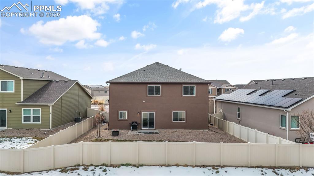 Snow covered rear of property featuring a fenced backyard, stucco siding, a residential view, and a shingled roof