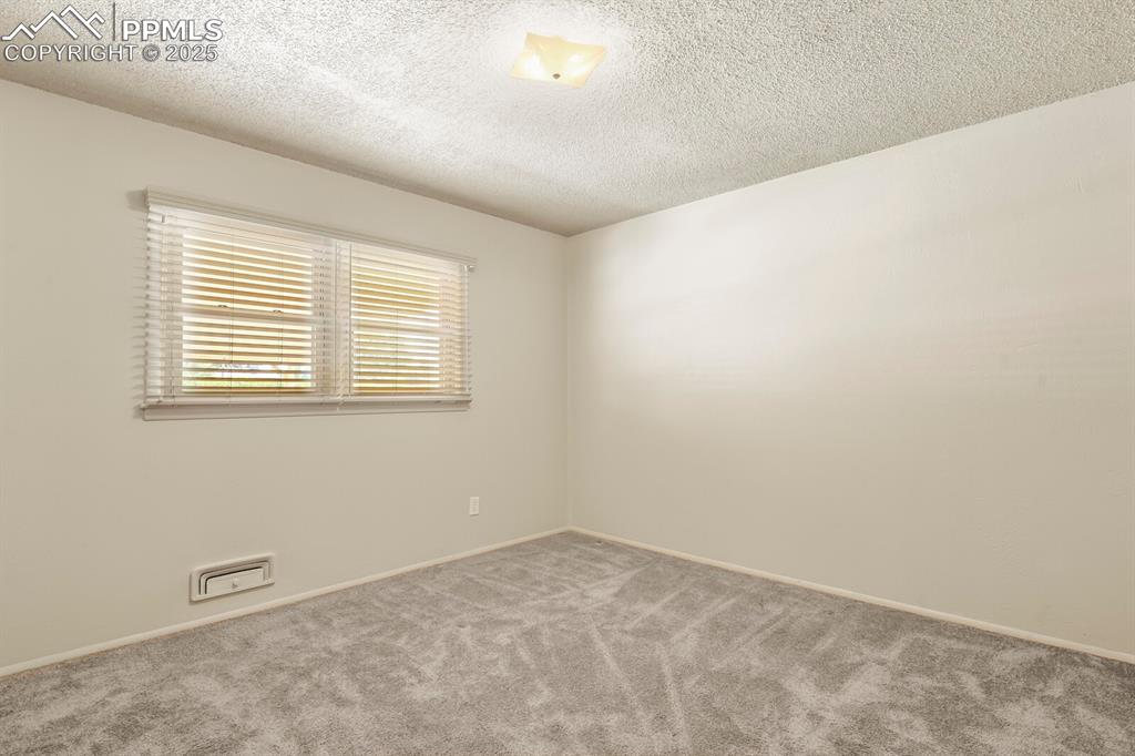 Bedroom featuring carpet floors and large window with wood blinds