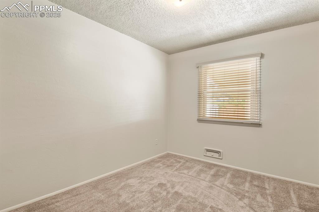 Spare room featuring carpet floors, window with wood blinds