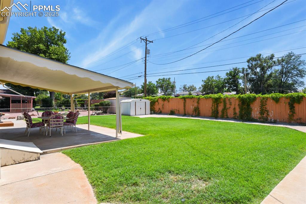 Fenced backyard with a storage shed and covered concrete patio