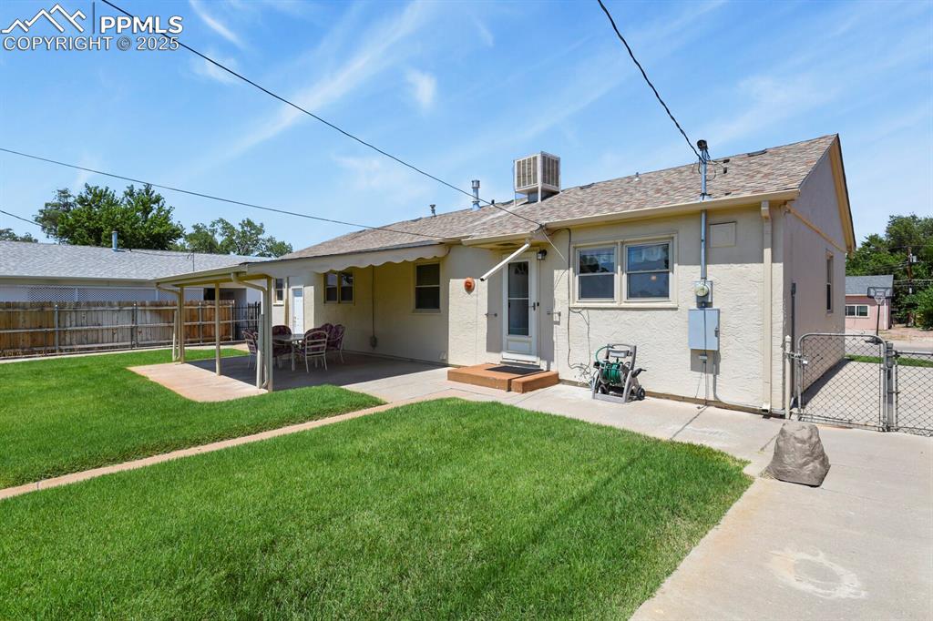 Rear view of house with a gate, stucco siding, a patio, and roof with shingles