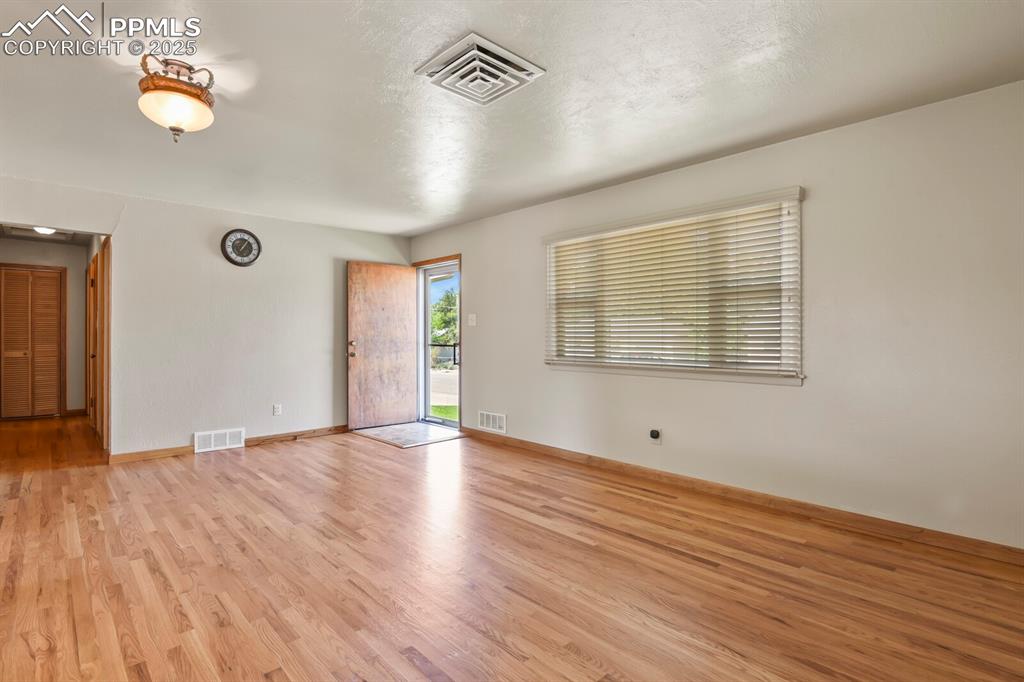 Family room with light wood finished floors, wood blinds, looking at front door