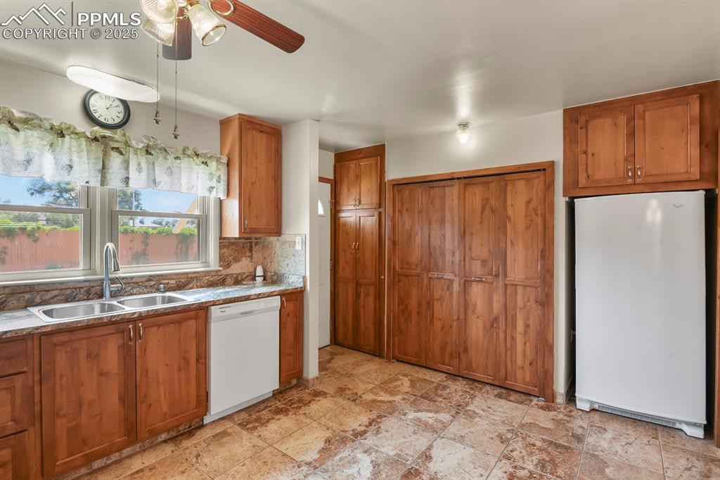Kitchen with white appliances, solid wood cabinets, ceiling fan, and backsplash